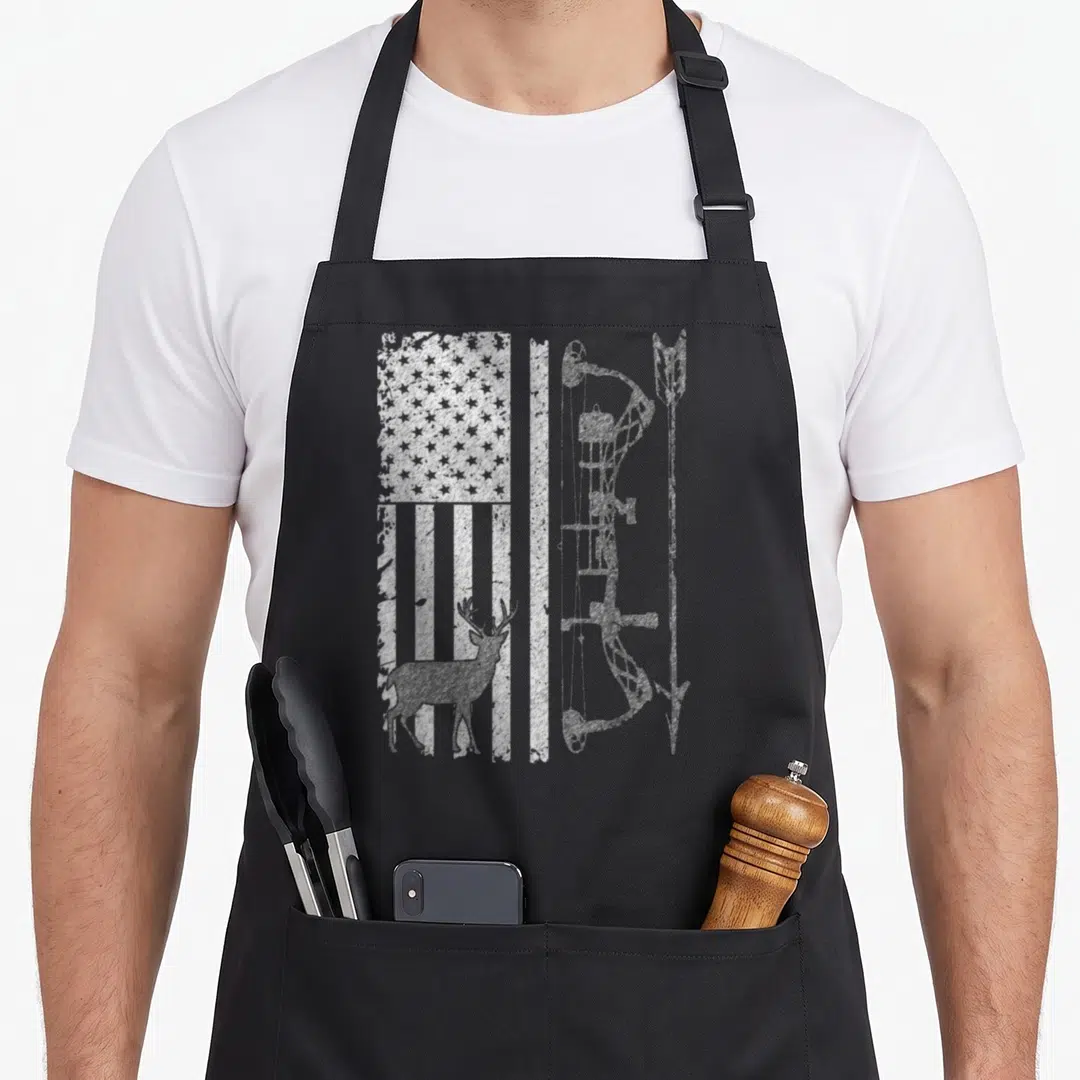 Hunting grill hunter apron - Distressed white USA flag, deer silhouette, and vertical bow printed on black fabric — shown on a black cotton canvas apron against a white background