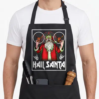 Hail ugly christmas apron - Screaming Santa with red pentagram and HAIL SANTA text in heavy metal style — shown on a black cotton canvas apron against a white background