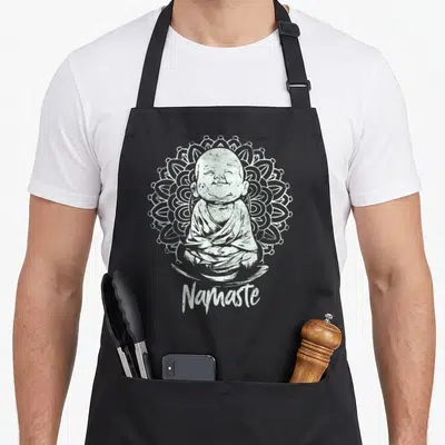 Buddha yoga apron - White seated Buddha inside circular mandala with Namaste script below — shown on a black cotton canvas apron against a white background