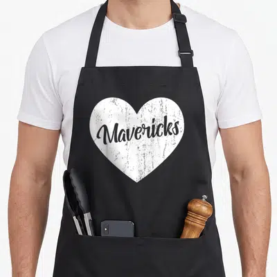 Maverick novelty apron - White distressed heart containing grey Mavericks script text — shown on a black cotton canvas apron against a white background