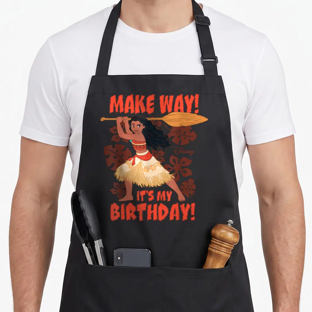 Way princess apron - Woman holding paddle with Make Way Its My Birthday text and brown leaves — shown on a black cotton canvas apron against a white background