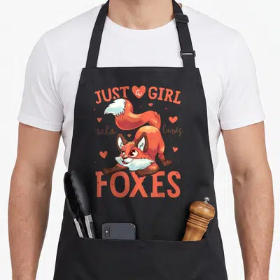 Retro animal fox print apron - Cartoon fox in orange and brown with hearts and text JUST a GIRL who loves FOXES — shown on a black cotton canvas apron against a white background