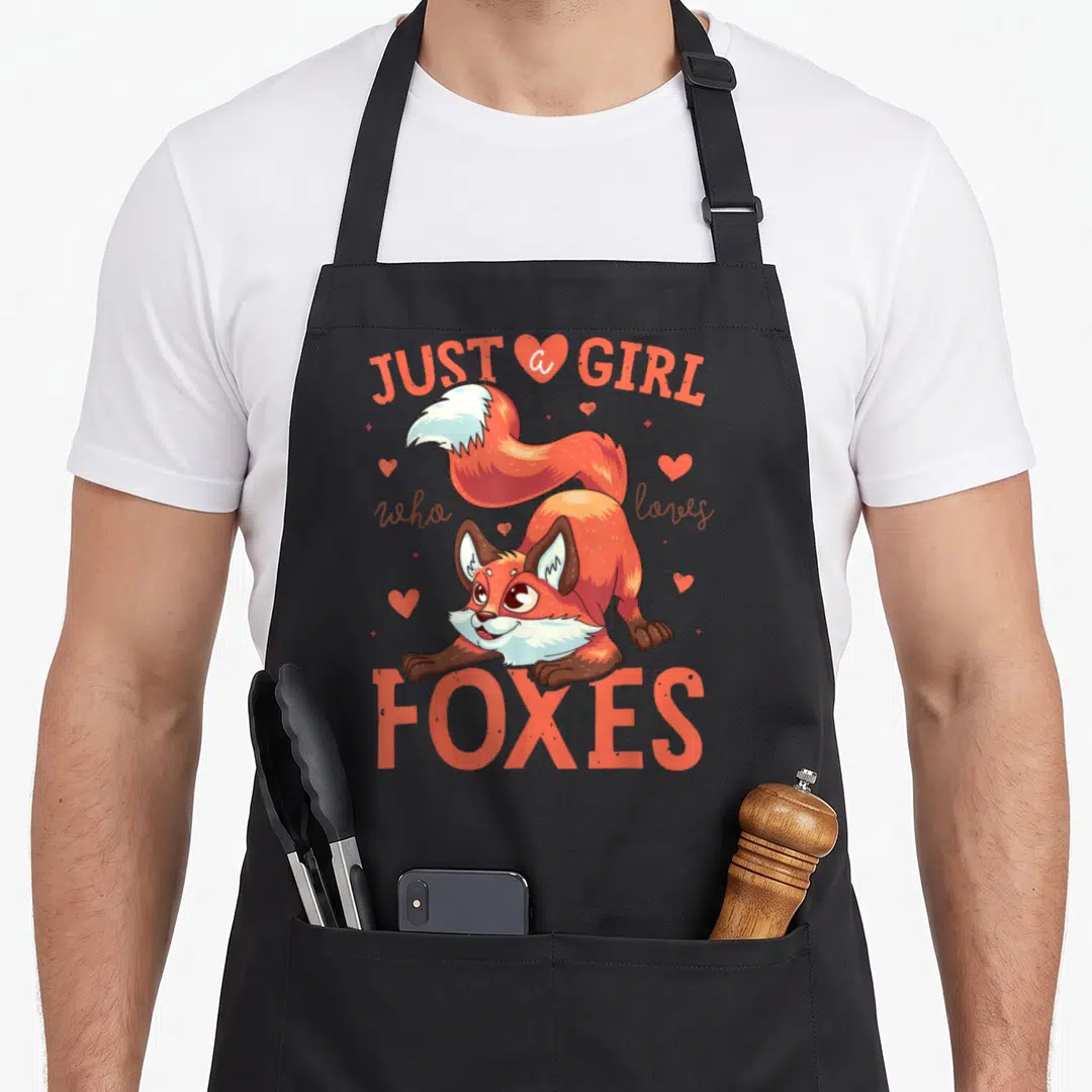 Retro animal fox print apron - Cartoon fox in orange and brown with hearts and text JUST a GIRL who loves FOXES — shown on a black cotton canvas apron against a white background