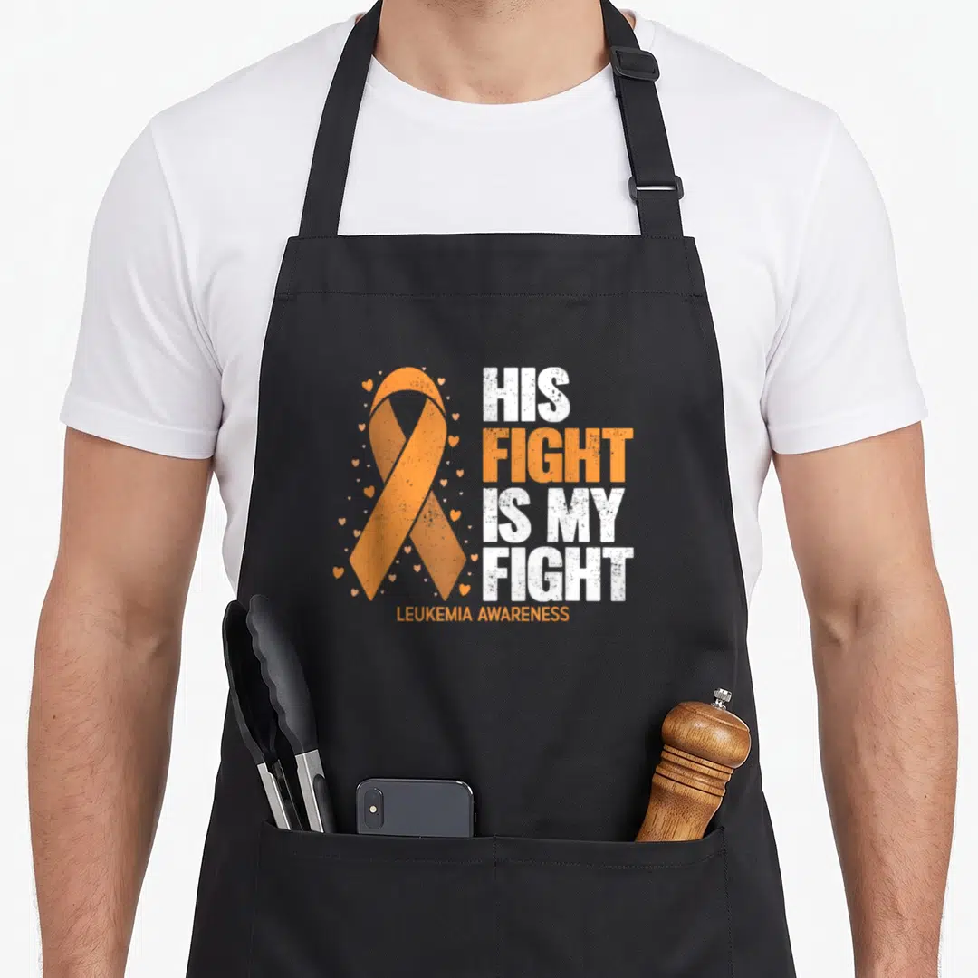 His leukemia awareness apron - Orange awareness ribbon with small hearts and stacked His Fight Is My Fight text — shown on a black cotton canvas apron against a white background