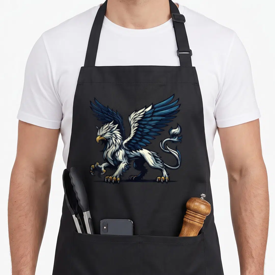 Legendary griffin apron - Cartoon griffin in dark blue, white, and gold standing with wings spread — shown on a black cotton canvas apron against a white background
