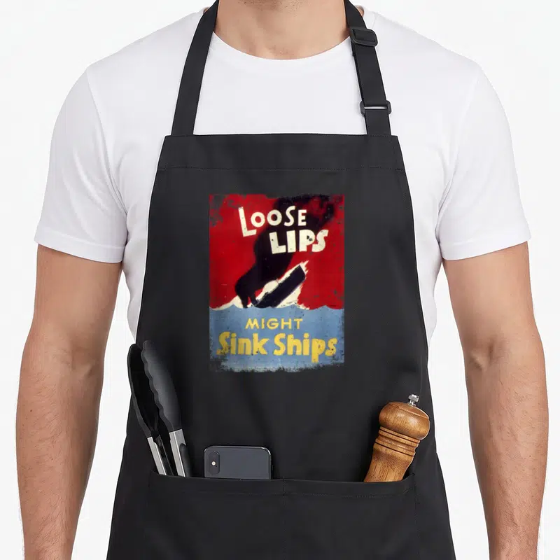 Loose ww2 apron - Retro poster print reading Loose Lips Might Sink Ships with silhouette and ship over blue water — shown on a black cotton canvas apron against a white background