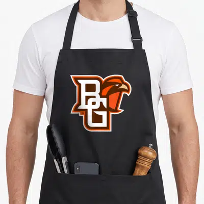 Icon falcon apron - BG letters with falcon head integrated, outlined in white and orange — shown on a black cotton canvas apron against a white background