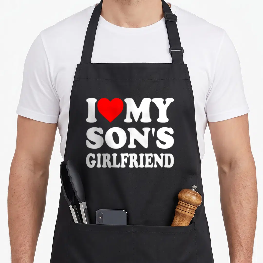 Son gathering apron - Red heart between I and MY above SON'S GIRLFRIEND in white block letters — shown on a black cotton canvas apron against a white background