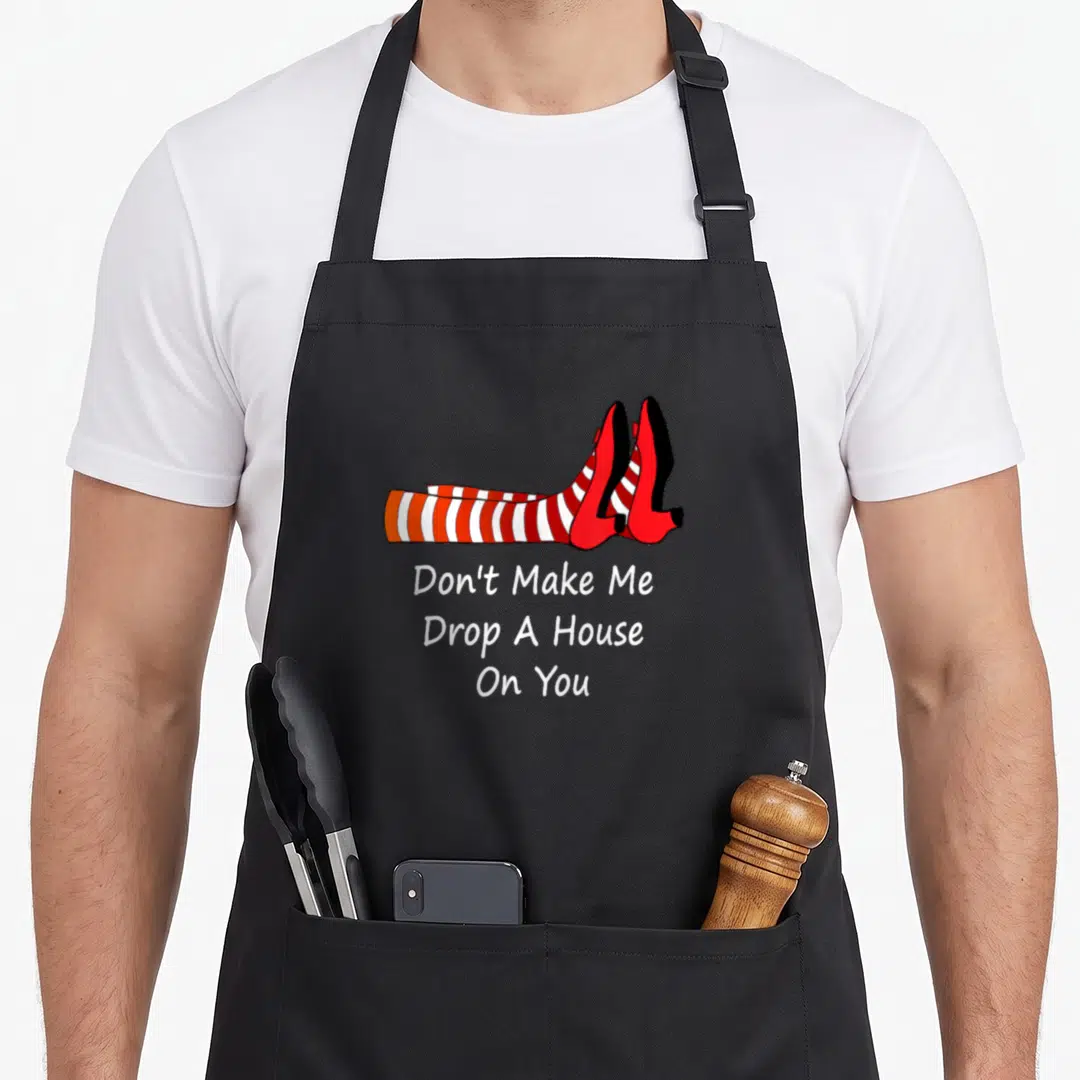 Drop novelty apron - Cartoon legs in red white stripes and red shoes above sarcastic text — shown on a black cotton canvas apron against a white background