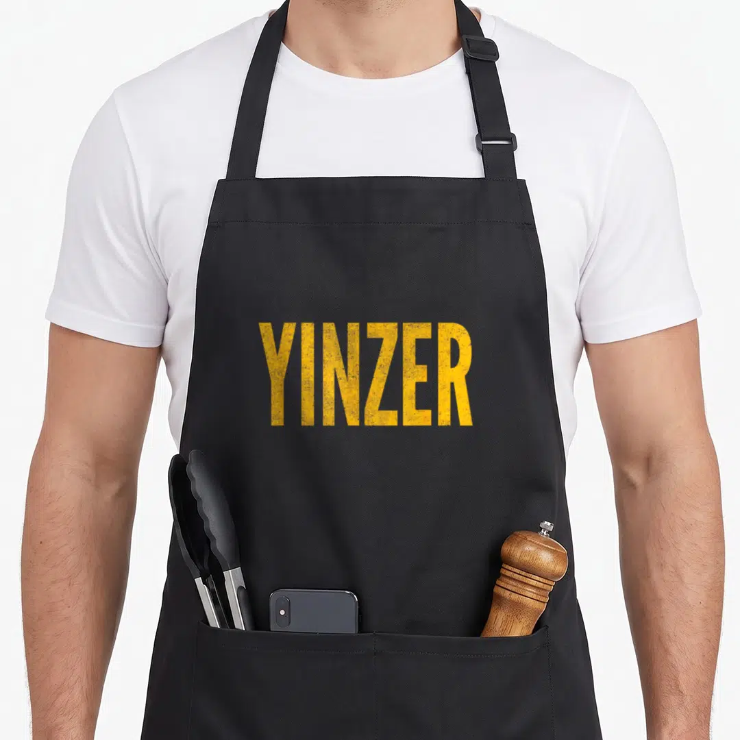 Yinzer theme aprons - Yellow distressed YINZER text on grey background — shown on a black cotton canvas apron against a white background