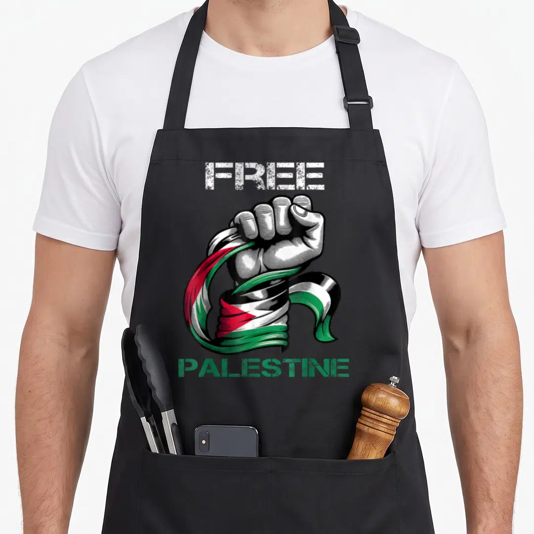 Strip palestine apron - Clenched fist wrapped in Palestinian flag with FREE PALESTINE text — shown on a black cotton canvas apron against a white background