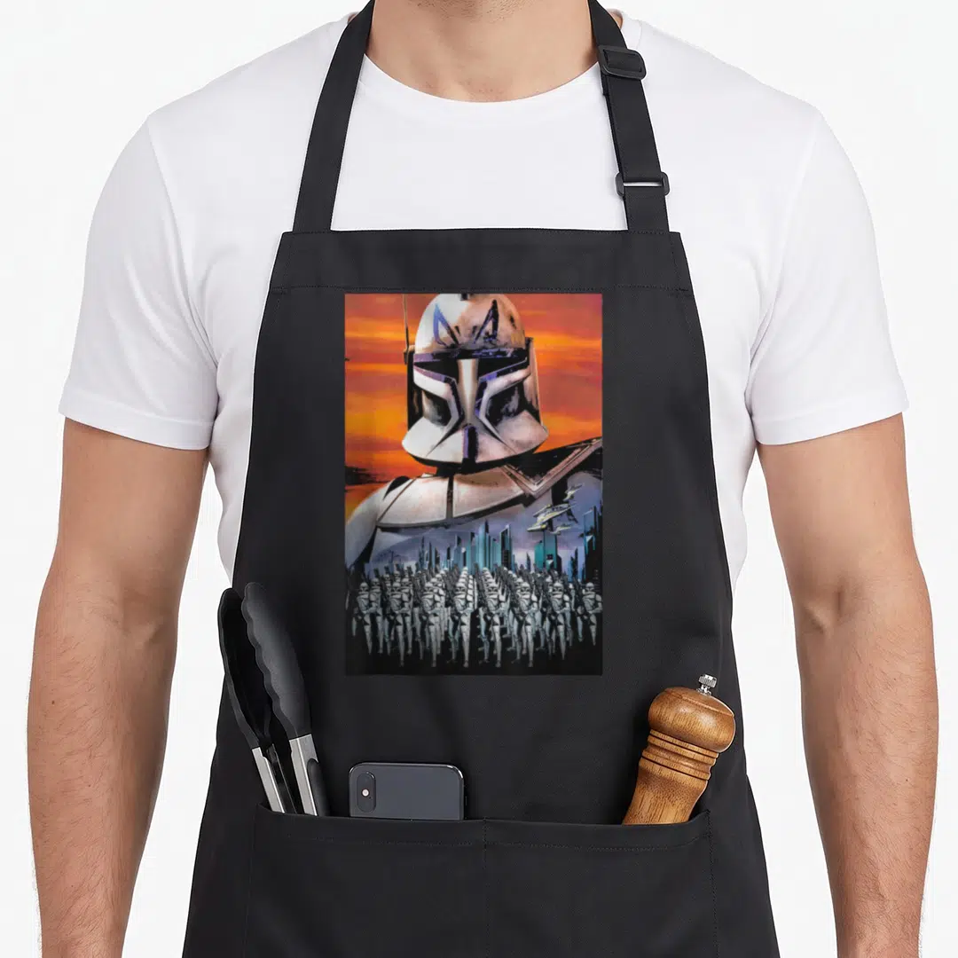 Captain t-rex apron - Helmeted soldier over flying spaceships and standing stormtroopers on orange background — shown on a black cotton canvas apron against a white background