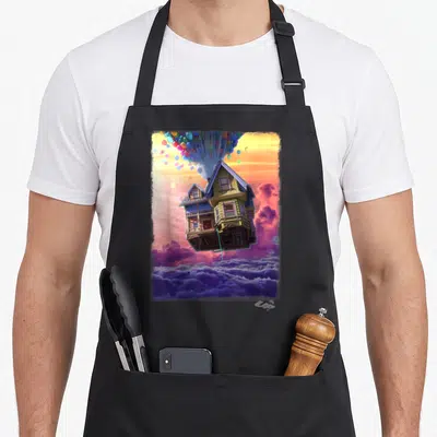 Watercolor flying apron - House lifted by multicolored balloons floating above purple clouds with Up text — shown on a black cotton canvas apron against a white background