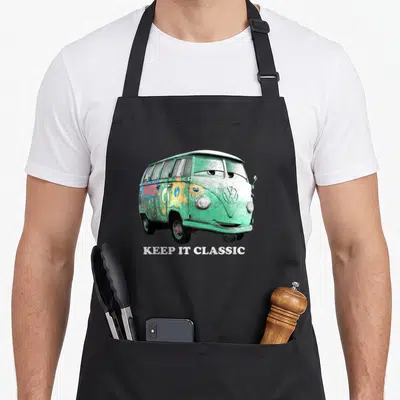 Fillmore car apron - Green VW bus with yellow flowers and white KEEP IT CLASSIC text — shown on a black cotton canvas apron against a white background