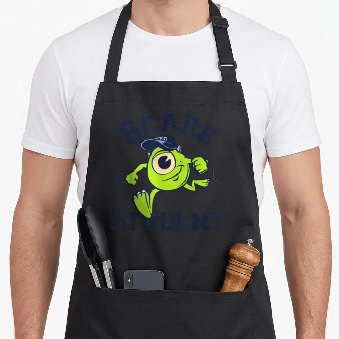 Monster student aprons - Lime green running one-eyed monster between two 13s under arched SCARE and straight STUDENT — shown on a black cotton canvas apron against a white background