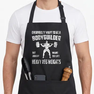 Perfect bodybuilding apron - White distressed text and bodybuilder lifting barbell graphic — shown on a black cotton canvas apron against a white background