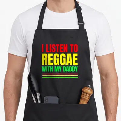 Reggae daddy apron - I LISTEN TO REGGAE WITH MY DADDY text in red yellow green with three wavy lines — shown on a black cotton canvas apron against a white background