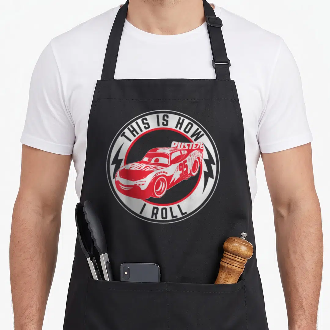 Roll car apron - Red race car with THIS IS HOW I ROLL text in circular logo — shown on a black cotton canvas apron against a white background