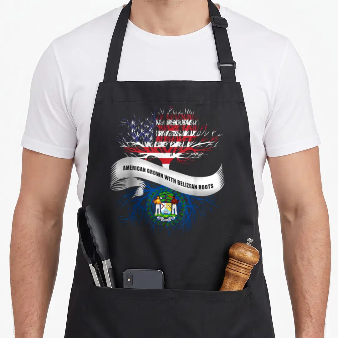 Root belizean apron - Tree with US flag canopy, blue roots, Belize coat of arms, white ribbon with text — shown on a black cotton canvas apron against a white background