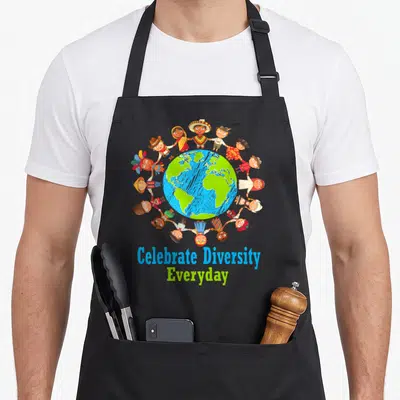 Celebrate teacher apron - Cartoon children in traditional clothes holding hands around globe with text — shown on a black cotton canvas apron against a white background
