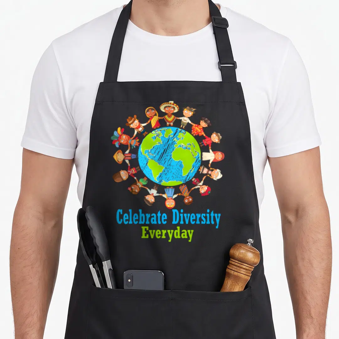 Celebrate teacher apron - Cartoon children in traditional clothes holding hands around globe with text — shown on a black cotton canvas apron against a white background