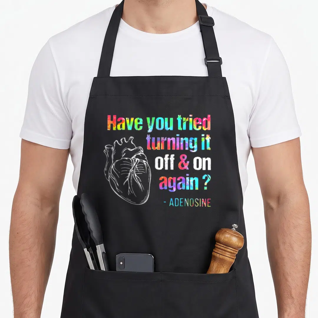 Tried adenosine turning apron - White line-art heart beside rainbow watercolor text reading Have you tried turning it — shown on a black cotton canvas apron against a white background