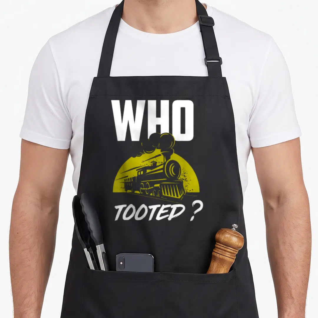 Tooted railroad train apron - Retro steam train graphic with text WHO TOOTED ? in white and olive green — shown on a black cotton canvas apron against a white background