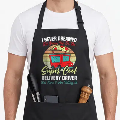 Ride food aprons - Red delivery truck with pizza slice on roof and stacked inspirational quote text — shown on a black cotton canvas apron against a white background