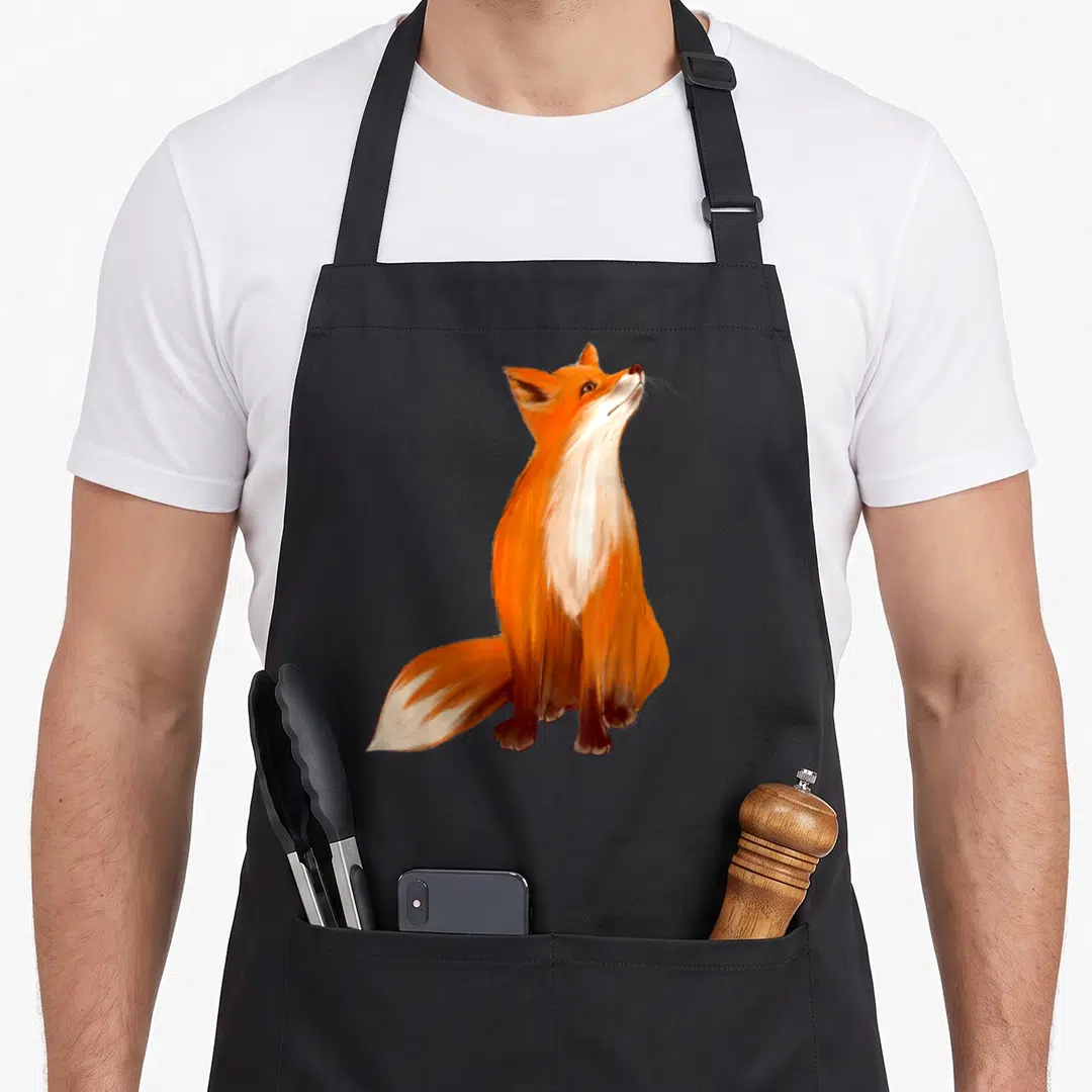 Watercolor fox aprons - Realistic orange and white fox sitting in profile looking upward — shown on a black cotton canvas apron against a white background