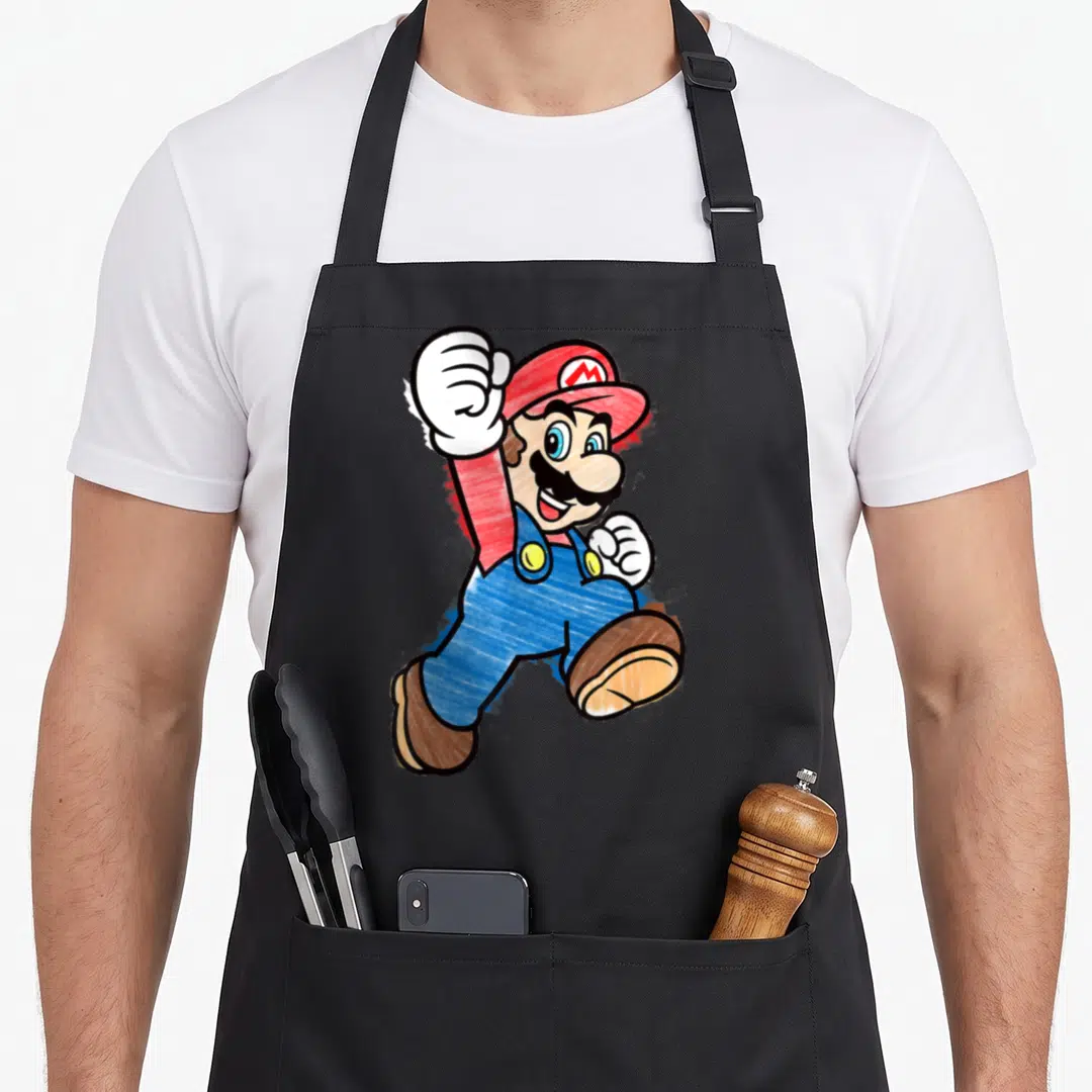 Funny markers apron - Cartoon Mario jumping with raised fist wearing red hat and blue overalls — shown on a black cotton canvas apron against a white background