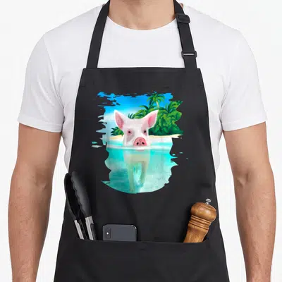 Bahamas holiday apron - Realistic pink pig swimming in turquoise water with palm trees and blue sky in torn frame — shown on a black cotton canvas apron against a white background