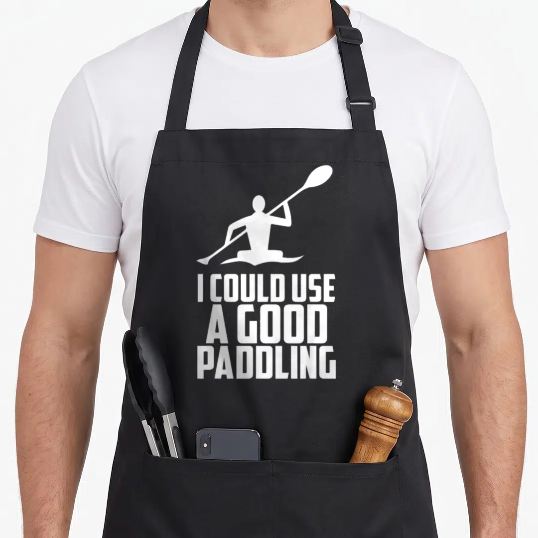 Kayak canoe apron - White kayaker silhouette above stacked text I could use a good paddling — shown on a black cotton canvas apron against a white background