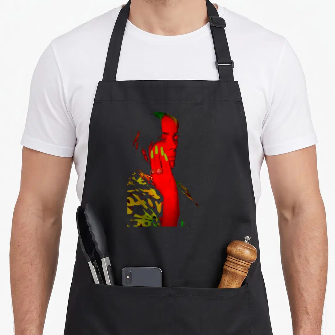 Eilish novelty apron - Color inverted photo of a woman in red yellow and green with hand on face — shown on a black cotton canvas apron against a white background