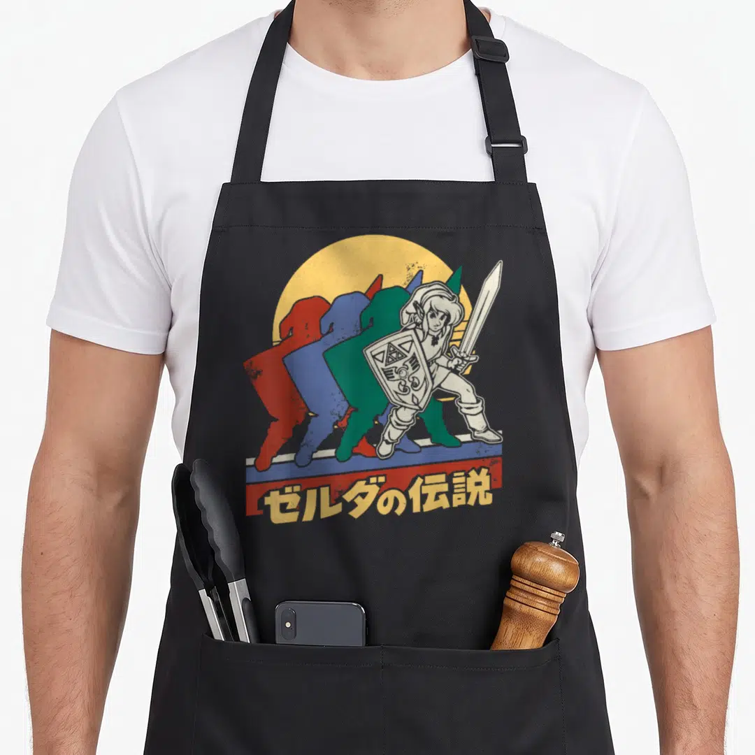 Link legend apron - Retro Link silhouettes in red blue green yellow with Japanese text on striped bar — shown on a black cotton canvas apron against a white background