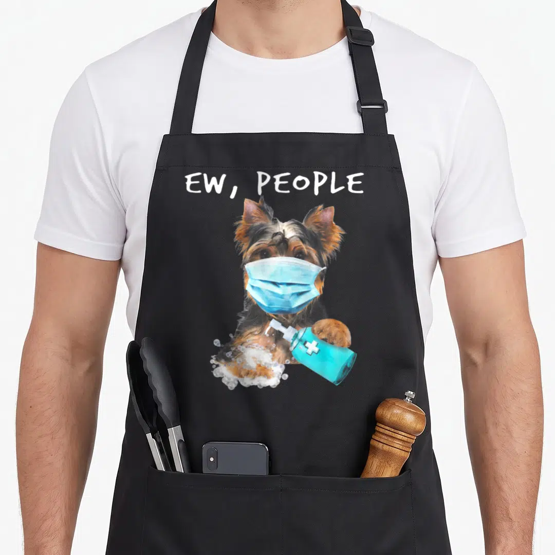 Yorkshire dog face apron - Dog in blue mask holding sanitizer bottle with ew people text — shown on a black cotton canvas apron against a white background