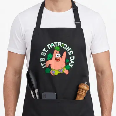 Squarepant st patrick day aprons - Patrick Star cartoon with IT'S ST. PATRICK'S DAY text and shamrocks in pink green — shown on a black cotton canvas apron against a white background