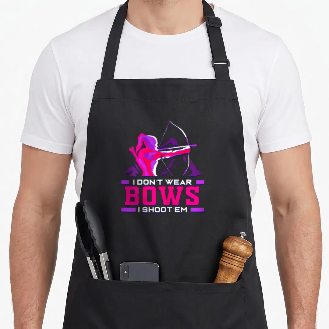Archer bow apron - Cartoon archer in pink and purple above stacked text reading I don't wear bows I shoot em — shown on a black cotton canvas apron against a white background