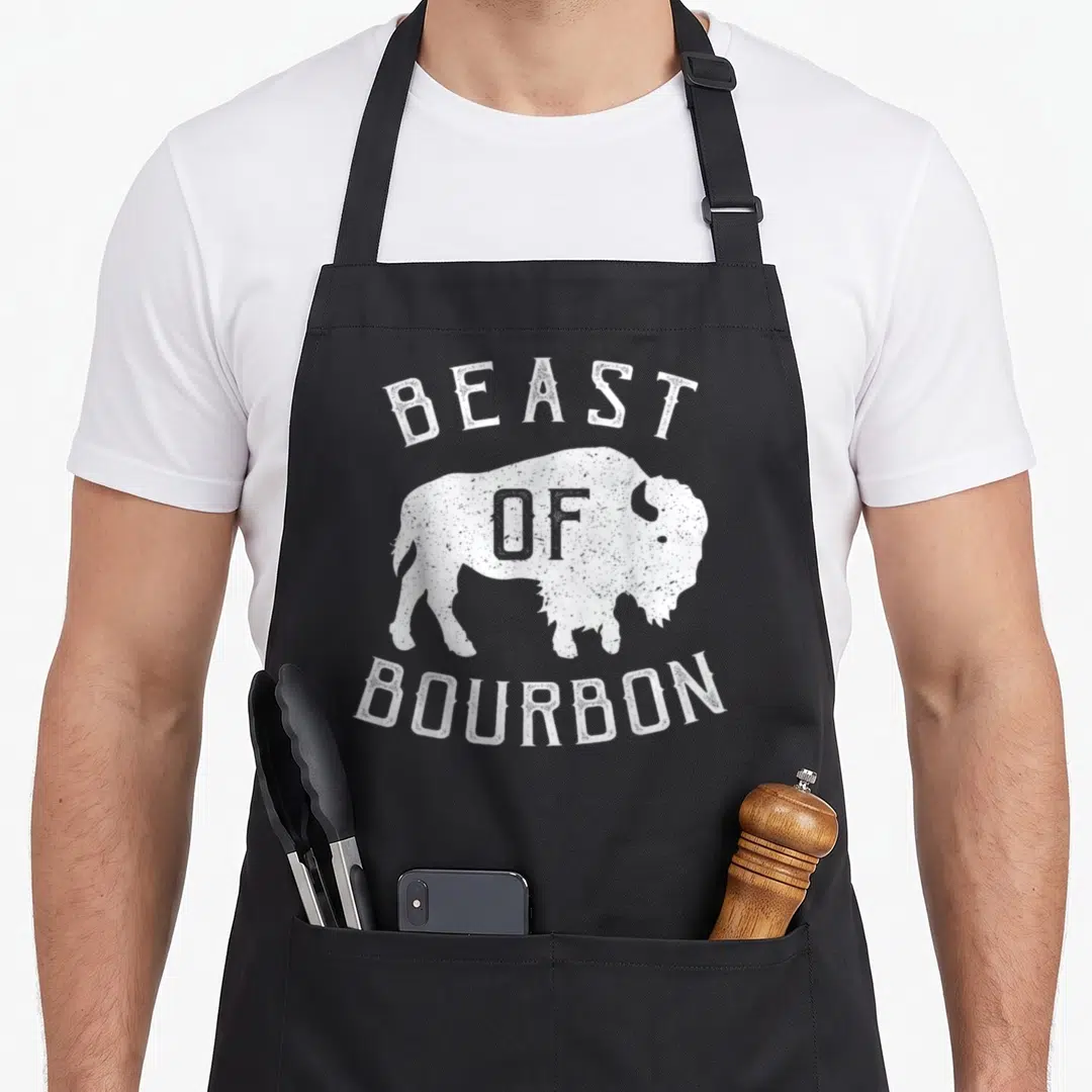 Beast buffalo apron - Distressed white bison silhouette with Beast of Bourbon text arched above and below — shown on a black cotton canvas apron against a white background