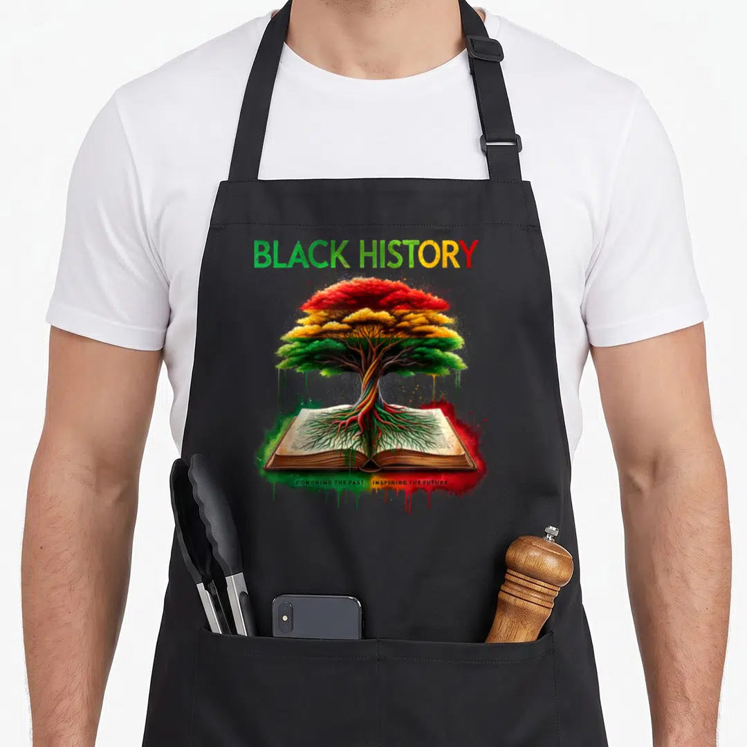 Inspiring african american aprons - Tree with red yellow green leaves growing from open book with black history text — shown on a black cotton canvas apron against a white background