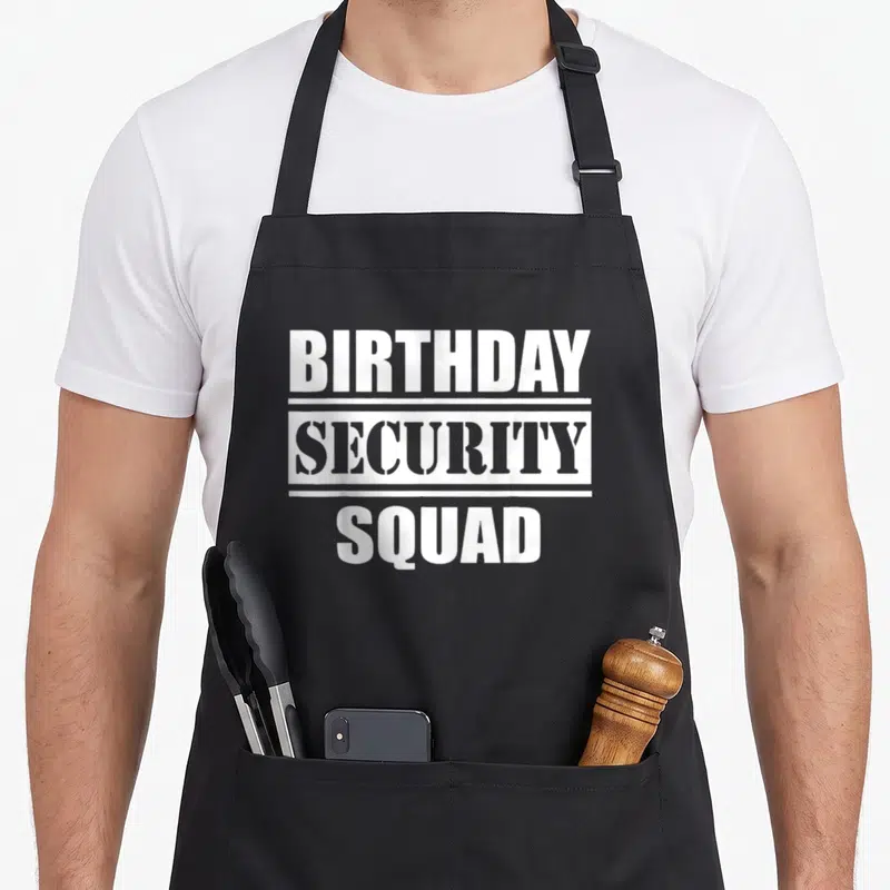 Security squad birthday apron - White stacked text BIRTHDAY SECURITY SQUAD with horizontal bars — shown on a black cotton canvas apron against a white background
