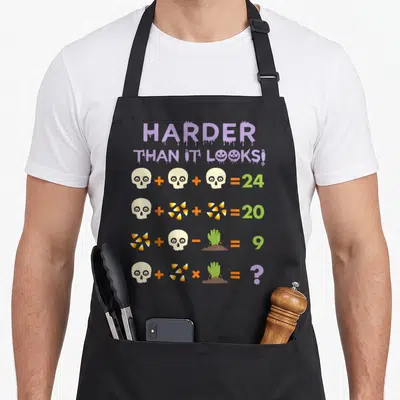 Quiz teacher apron - Purple dripping text above math equations using skulls, candy corn, and zombie hands as variables — shown on a black cotton canvas apron against a white background
