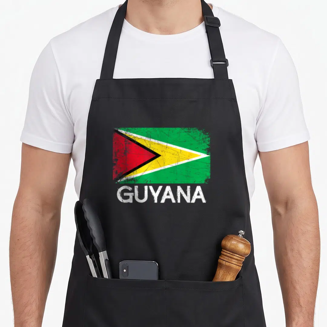 Guyanese flag guyana apron - Distressed Guyana flag graphic above white GUYANA text on black fabric — shown on a black cotton canvas apron against a white background