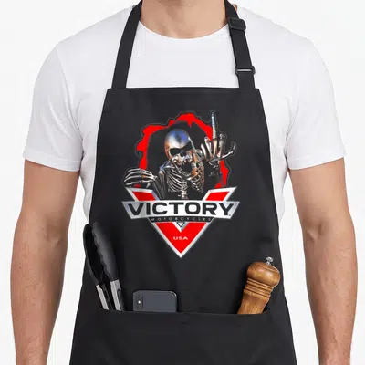 Motor skeleton apron - Metallic skeleton behind red V logo with Victory Motorcycles USA text — shown on a black cotton canvas apron against a white background