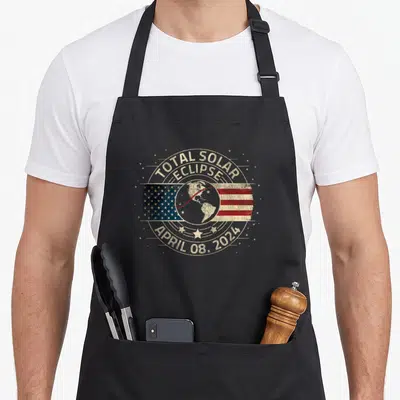 Totality eclipse apron - Distressed circular emblem with earth over horizontal USA flag and arched text reading TOTAL — shown on a black cotton canvas apron against a white background
