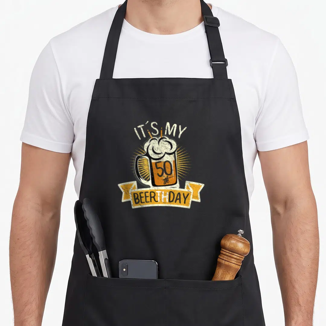 Beerth birthday apron - Distressed beer mug with 50th and three candles under IT'S MY BEERTHDAY banner — shown on a black cotton canvas apron against a white background