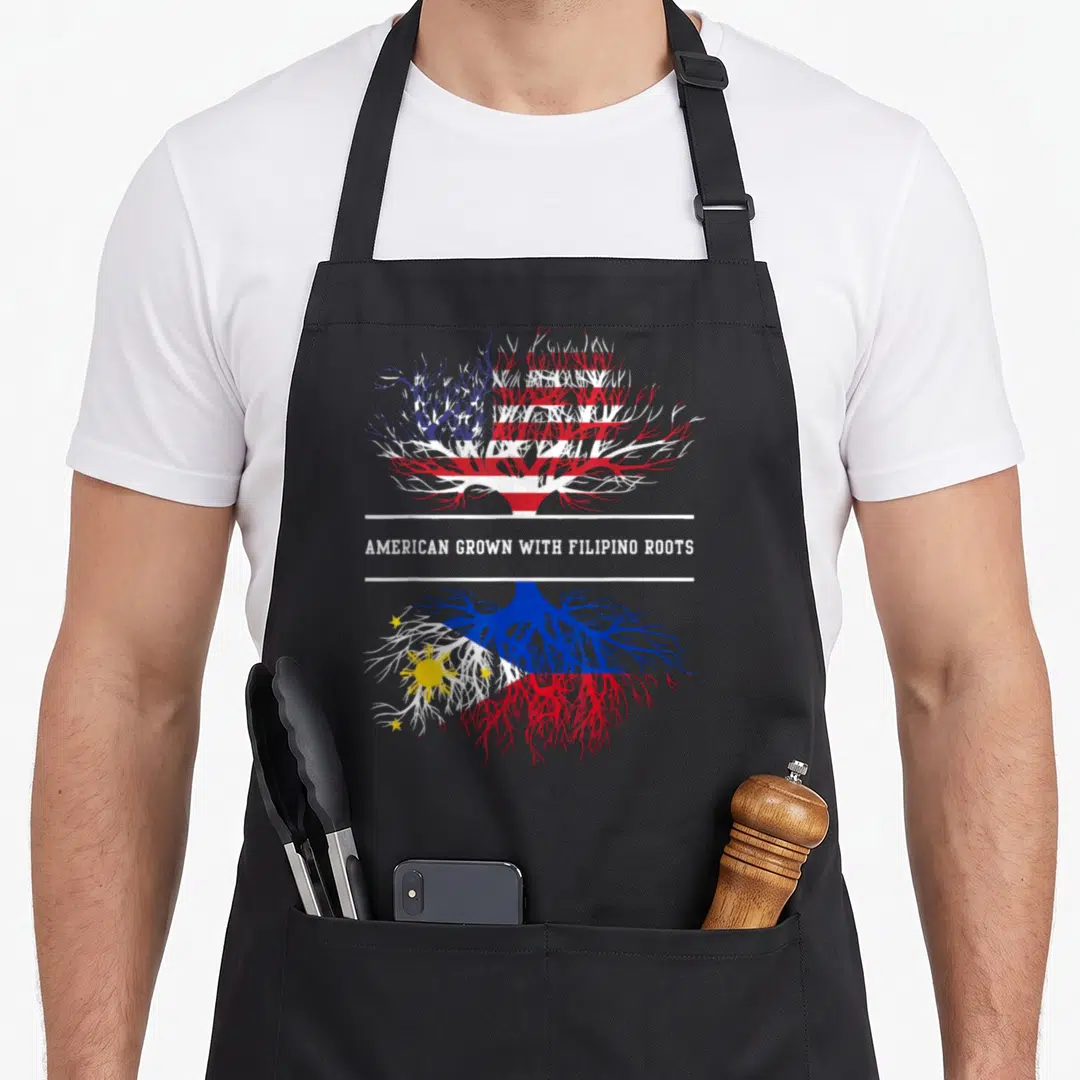 Root filipino american apron - Tree with US flag canopy and Philippine flag roots, text AMERICAN GROWN WITH FILIPINO — shown on a black cotton canvas apron against a white background