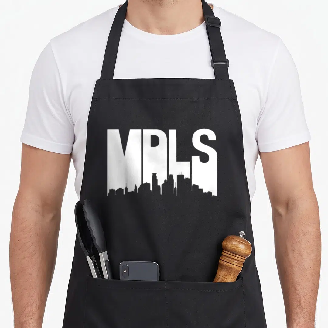 Skyline minneapolis apron - White MPLS text with Minneapolis skyline silhouette integrated into the bottom — shown on a black cotton canvas apron against a white background