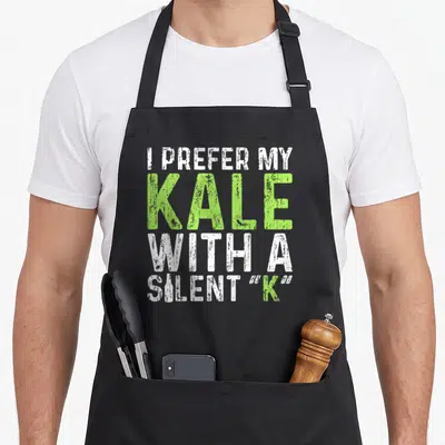 Prefer beer apron - White and green typography reading I Prefer My Kale With A Silent K including a bottle icon — shown on a black cotton canvas apron against a white background