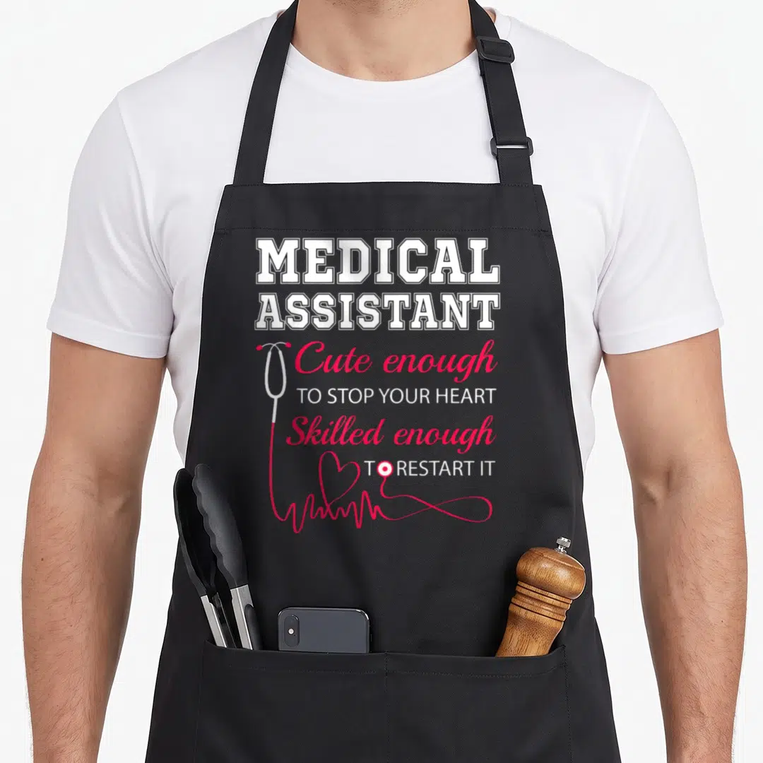 Stop nurse apron - Medical Assistant text with red stethoscope heart and EKG line — shown on a black cotton canvas apron against a white background