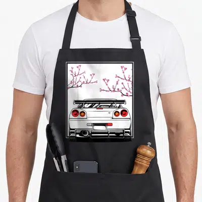 Cherry design imports vintage apron - Rear view white car with pink cherry blossom branches in line art style — shown on a black cotton canvas apron against a white background
